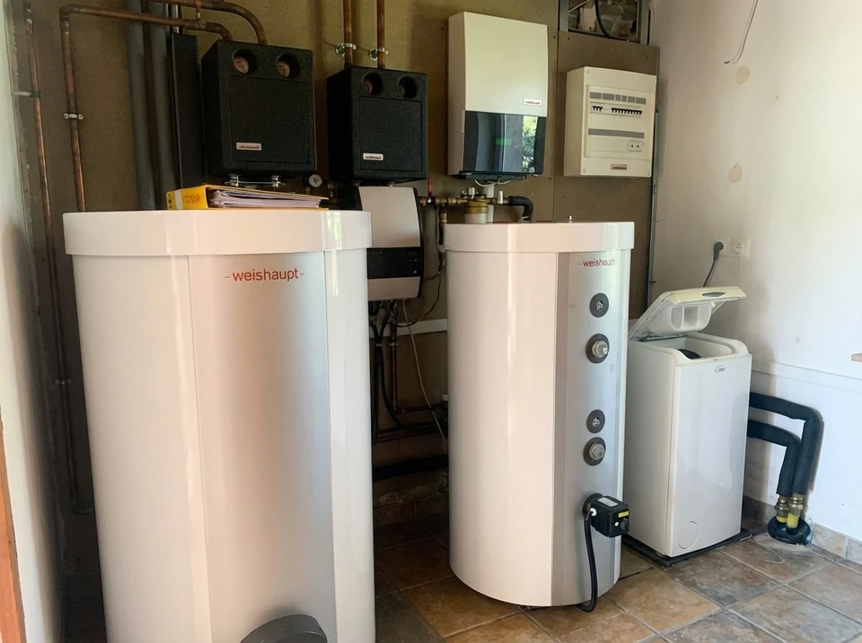 Intérieur moderne avec installation de chauffage domestique comprenant chaudière biomasse rouge avec écran numérique, réservoir de stockage cylindrique blanc isolé, système d'alimentation automatique par vis sans fin, conduits d'évacuation fumées